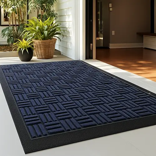 Dark blue textured entrance mat with a geometric pattern placed at a modern home doorway, designed to trap dirt and moisture while providing a clean, stylish entry area.