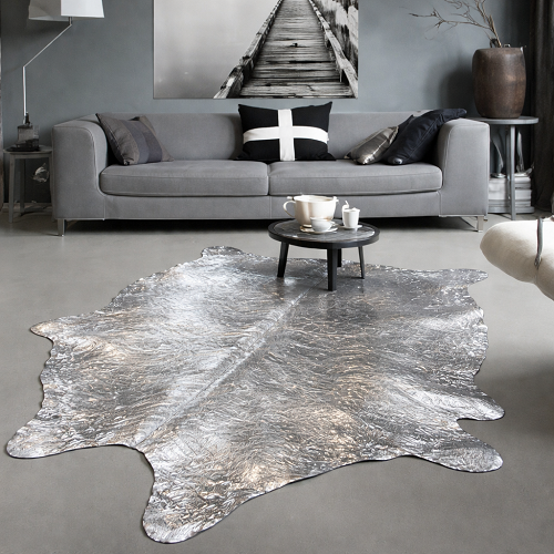 Metallic silver cowhide rug under a small coffee table in a modern gray living room.