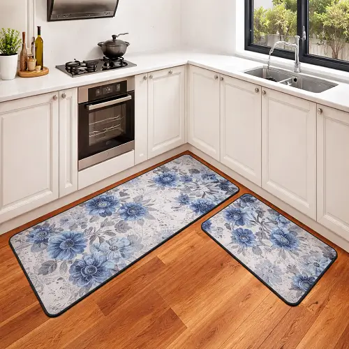 Two blue floral kitchen mats placed on a wooden floor in a modern white kitchen near the sink and countertop.